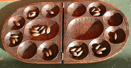 My board, from Cameroon. On this board players would sit left and right. The pieces are seeds.
